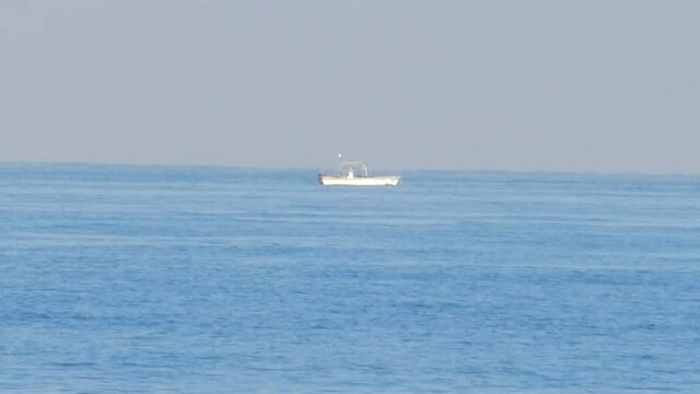 A small motor boat moored on the water remains still as calm seas move the image slightly
