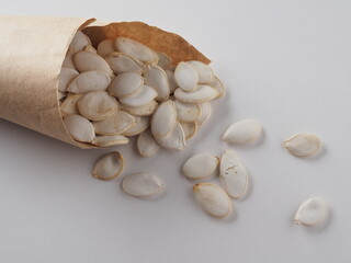 Pumpkin seeds in a paper bag on a white background