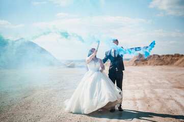 Fototapeta na wymiar Newlyweds in a career. The guy and the girl hug and hold colored smoke in their hands