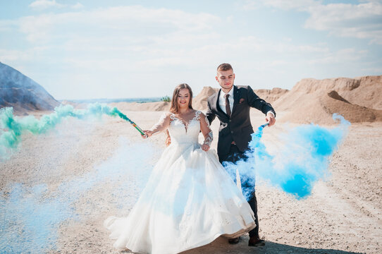 Newlyweds in a career. The guy and the girl hug and hold colored smoke in their hands