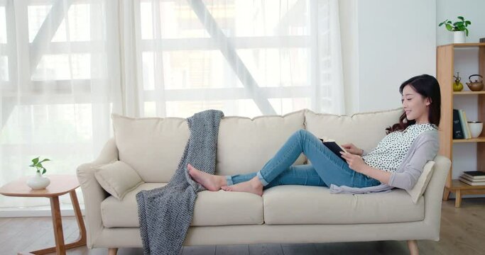 Happy young woman reading book in living room,4K