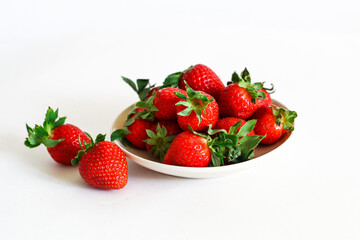 Strawberry berry with green leaf in a plate, isolated on a white background, white table. berries and food