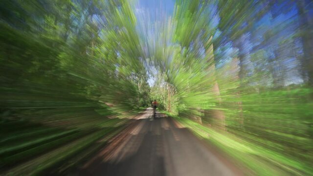 The back view of the female cyclist riding a bicycle in the Divoka Sarka natural park in Prague on a summer day.