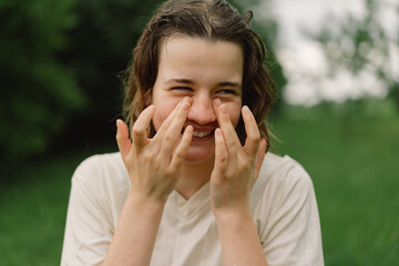 Close-Up Portrait Of Teenager Girl. Cheerful Teen Girl With Pronounced Face From Sprayed Small Splashes Of Water Or Warm Summer Rain In Outdoors.