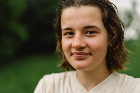 Close-Up Portrait Of Teenager Girl. Cheerful Teen Girl With Pronounced Face From Sprayed Small Splashes Of Water Or Warm Summer Rain In Outdoors.