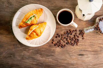 hot coffee in white ceramic mug on old wooden table,croissant in white plate,coffee beans and coffee kettle