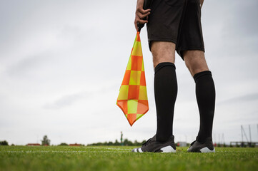 Soccer touchline referee - detail of legs and hand with the flag.