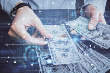 Double exposure of technology drawing hologram and us dollars bills and man hands. Data concept