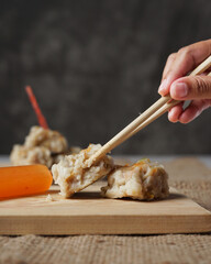 Siomay dim sum on a dark background. Siomay is thought to have come from Inner Mongolia. In Mandarin, siomay (shaoma). Indonesian dumplings generally use mackerel as the main ingredient. Focus blur.