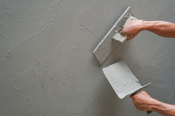 hand of worker plastering cement wall at construction site with copy space, selective focus