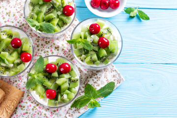 Healthy breakfast: yogurt parfait with cookies, banana and kiwi on a blue background. Place for text
