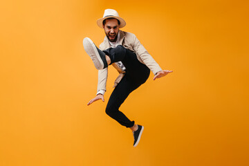 Fototapeta na wymiar Funny man in hat jumps on orange background