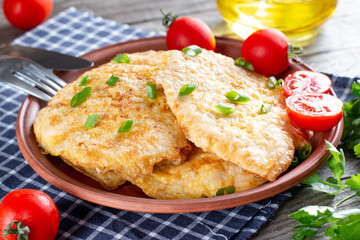 Fried chicken chop. Home fried chicken chop with tomatoes on a wooden table. Rustic style.