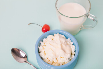 Cottage cheese in a blue bowl with sour cream and honey, a cup with milk. Morning breakfast.