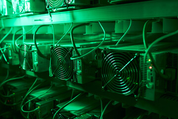 Bitcoin miners in large farm. ASIC mining equipment on stand racks mine cryptocurrency in steel...