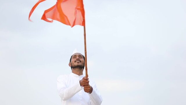 Young indian man (pilgrim) in traditional wear and waving religious flag.