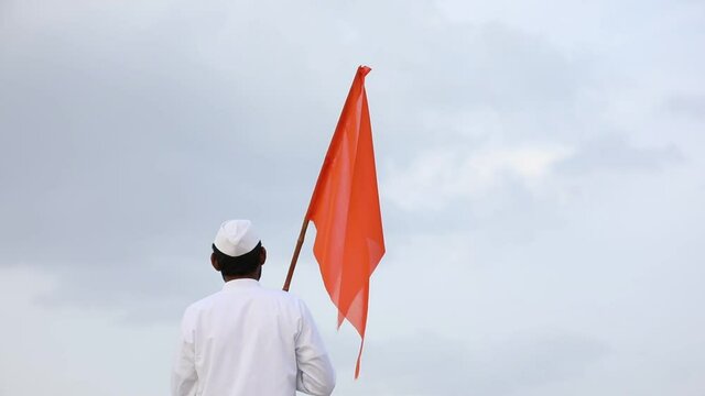 Young indian man (pilgrim) in traditional wear and waving religious flag.