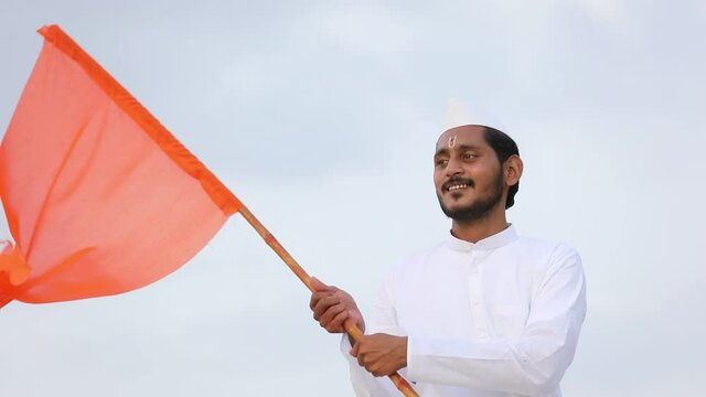 Young indian man (pilgrim) in traditional wear and waving religious flag.