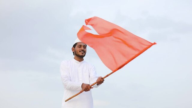 Young indian man (pilgrim) in traditional wear and waving religious flag.