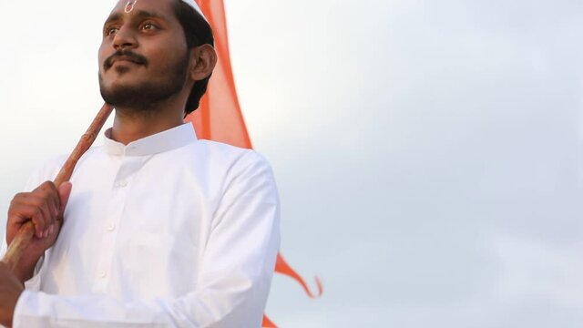 Young indian man (pilgrim) in traditional wear and waving religious flag.