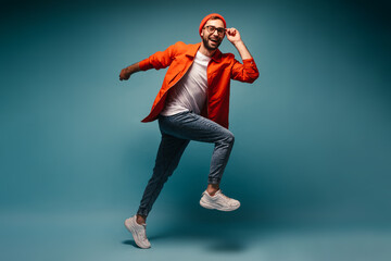 Fototapeta na wymiar Cool guy in good mood posing on blue background and jumping