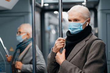 two women in protective masks standing in a subway car.