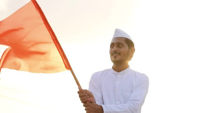 Young indian man (pilgrim) in traditional wear and waving religious flag.