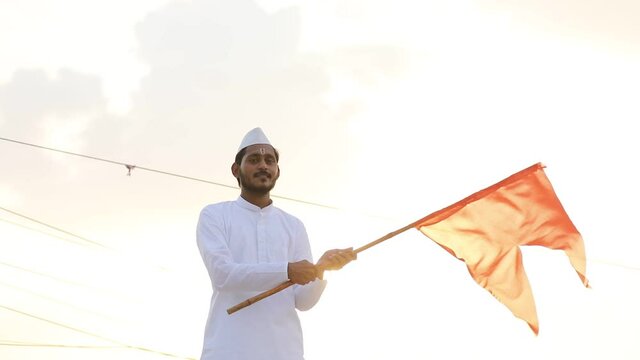 Young indian man (pilgrim) in traditional wear and waving religious flag.