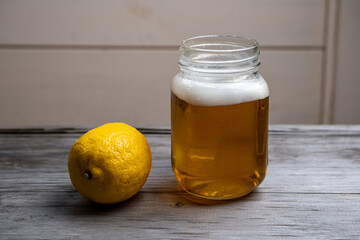 Lemonade in a mug and fresh lemon on a blurry wooden background. Selective focus. Space for lettering and design