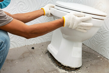 workerman performs repair of toilet bowl,  To repair the pipe from the toilet - obrazy, fototapety, plakaty