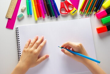 hand with pencils, the child draws in a notebook