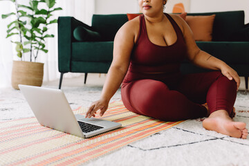 Body positive woman watching online workout video on laptop