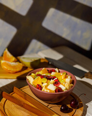 fresh organic fruit salad with oranges, grapes, pears and cherry on wooden background