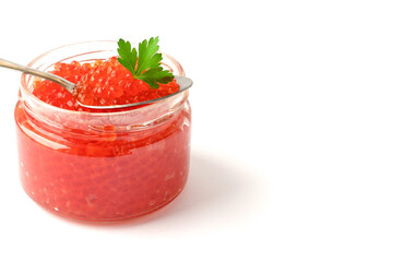 Red caviar in open glass jar with spoon and green parsley leaf on top. Close up. Copy space.