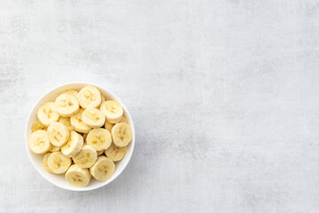 Many banana slices in white bowl. Top view