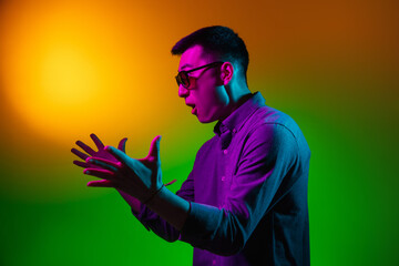 Portrait of Asian young man isolated on studio background in gradient green yellow neon light,...