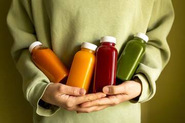 The woman is holding bottles of freshly squeezed juice in her hands. The concept of a healthy lifestyle, diet or detox, body care.