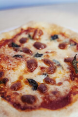 A close-up of a mini pizza in a disposable dish. Top view of takeaway food in fast food cafe. The photo shows mozzarella cheese, tomatoes, olives and various sausages. Meal for one person