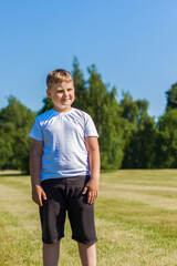 A cheerful child smiles with joy. I am happy to walk and play on the lawn in warm sunny weather in the park. the emotions of children on the face.