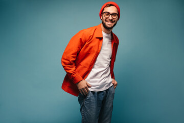 Handsome guy dressed in bright jacket and jeans looks into camera