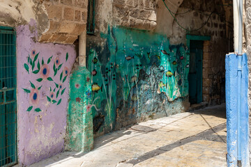 Old streets with walls decorated with drawings and other decorations in the old city of Acre in northern Israel