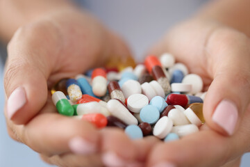 Multi-colored medical pills in female hands closeup