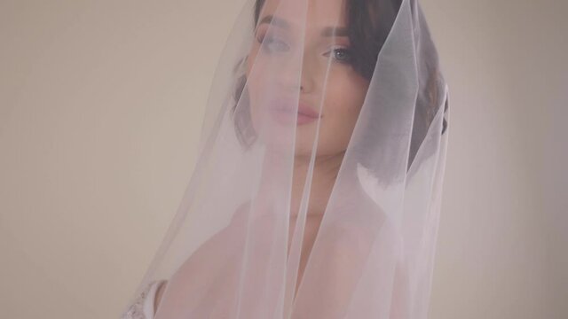 Close-up portrait of a bride in a dress with a veil that covers her head.