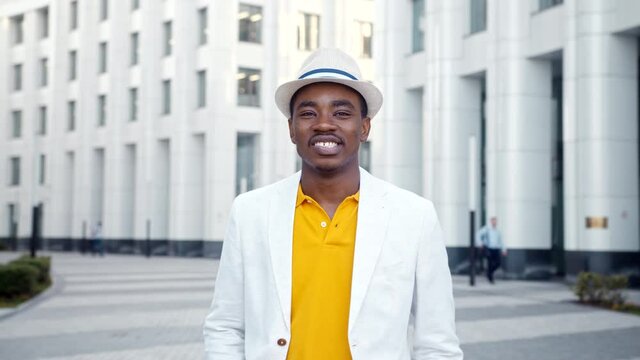 African American guy in white suit looks straight and smiles