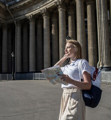 beautiful girl-guide, blonde, holding a map, in the afternoon. Drawing up a route for tourists. Resumption of sightseeing tours. 20.06.2021 Russia, St. Petersburg, city center