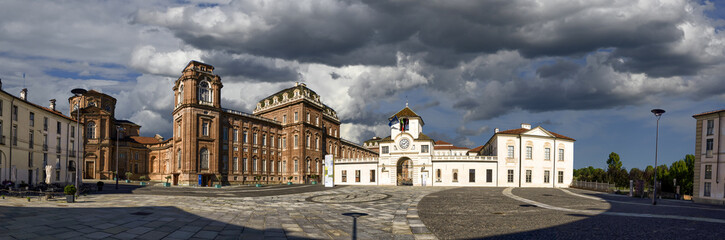 Fototapeta na wymiar Venaria Reale, Piedmont, Italy. July 2021. Large format panoramic photo of the piazza della repubblica. Highlights the clock tower: entrance to the royal palace. Beautiful summer day.