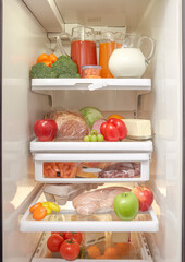 An open refrigerator with healthy fruits, vegetables, and meat 