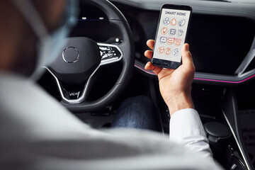 Young man in white shirt is sitting inside of a modern new automobile