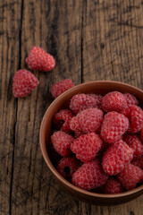 red fresh domestic raspberry at bowl on a rustic table top. space
