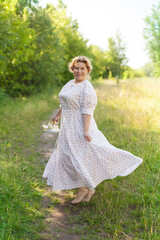 Fototapeta na wymiar a young happy woman walks barefoot in a field on a summer day, holding shoes in her hands. Model plus size. selective focus